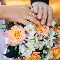 couple_showing_their_wedding_rings_on_top_of_bouquet.jpg